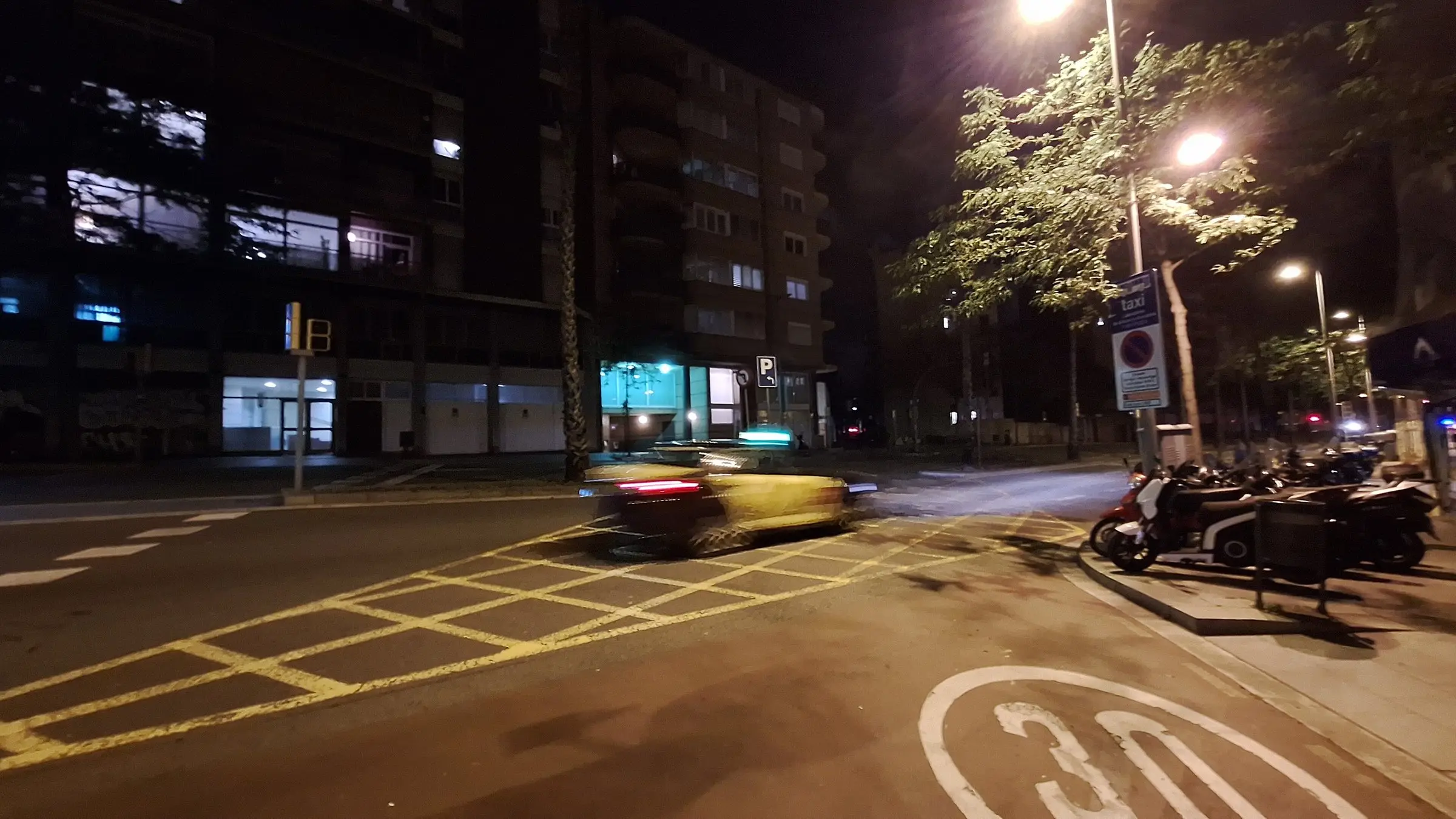 Calle de Barcelona a oscuras durante el apagón, con un coche pasando por un cruce
