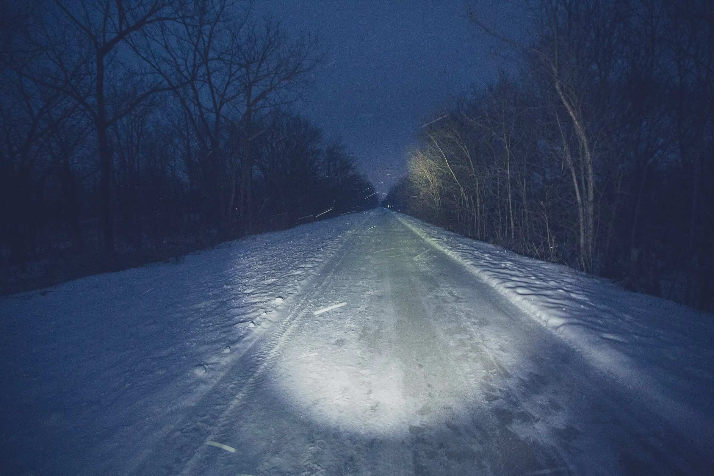 Haz de una linterna frontal iluminando un camino nevado de noche